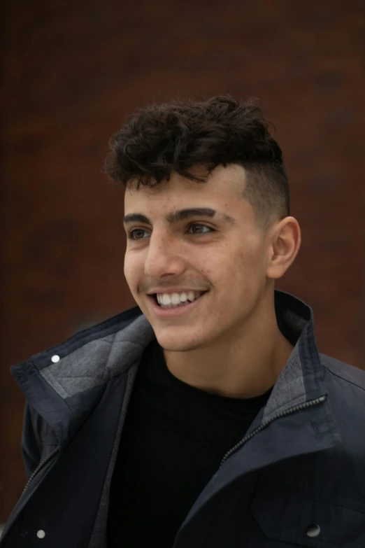 a close up of a person wearing a jacket, by Leo Michelson, sam nassour, cute young man, smileing nright, transgender