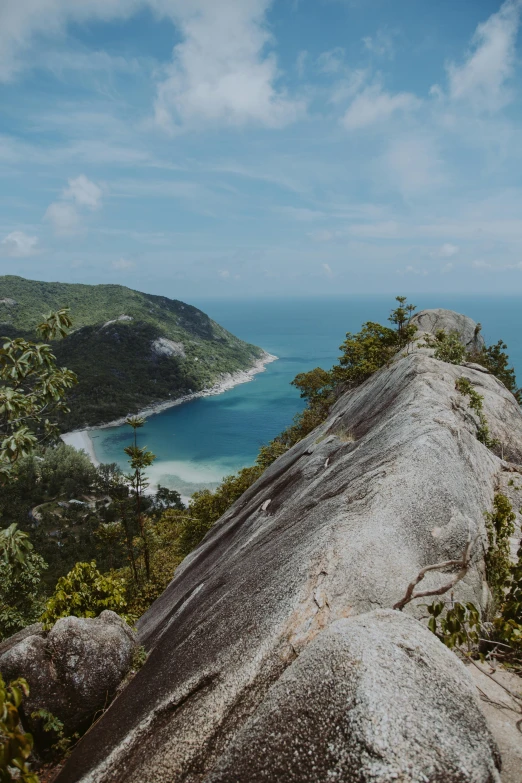 a large rock sitting on top of a lush green hillside, unsplash contest winner, sumatraism, view of sea, granite, slide show, cape