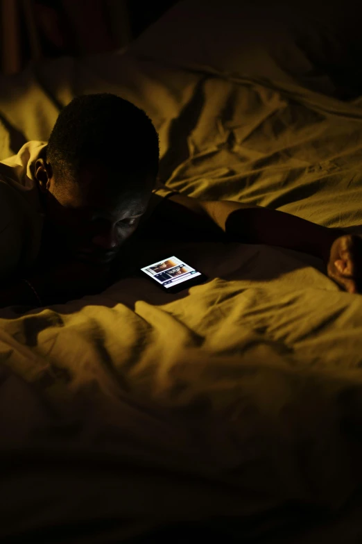 a person laying in bed with a cell phone, happening, dark-skinned, a boy, digital still, ios