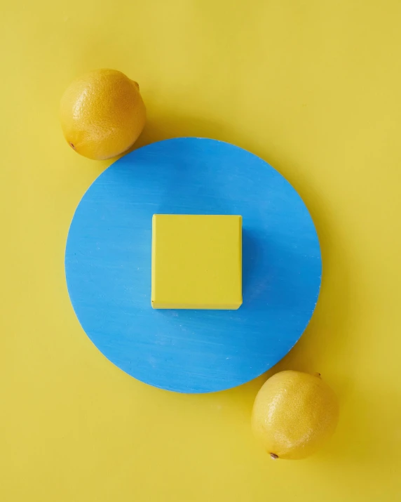 two lemons and a square on a blue plate, an abstract sculpture, inspired by Mondrian, trending on unsplash, solid cube of light, trending on dezeen, pantone, made of cheese