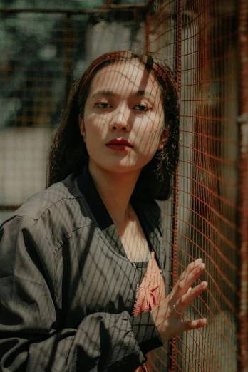 a woman standing in front of a fence, inspired by Gao Xiang, trending on pexels, neo-figurative, portrait image, female actress from korea, red mesh in the facede, ((portrait))