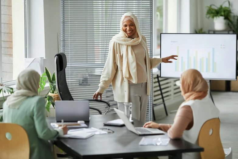 a woman giving a presentation to a group of people, by Everett Warner, pexels contest winner, hurufiyya, on a desk, muslim, hip corporate, wholesome