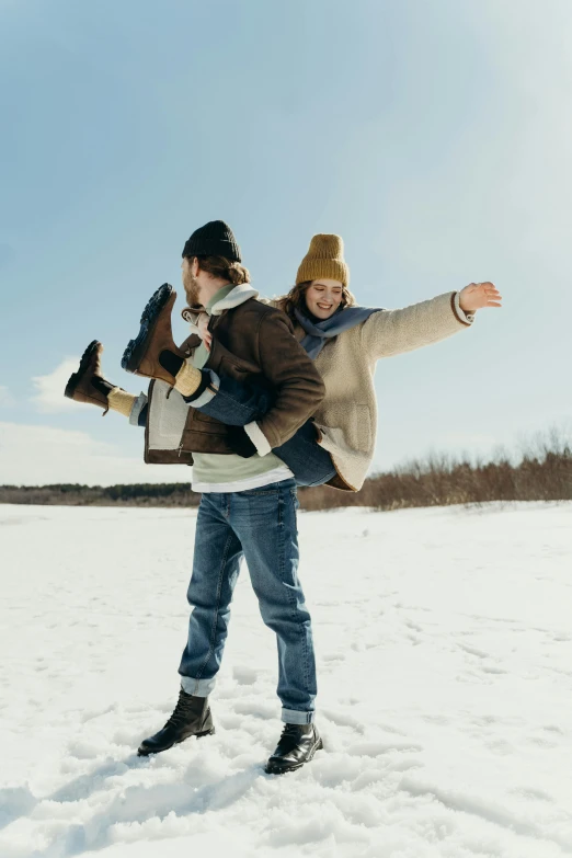 a man carrying a woman on his back in the snow, trending on pexels, wingspan style, (3 are winter, lookbook, arms out