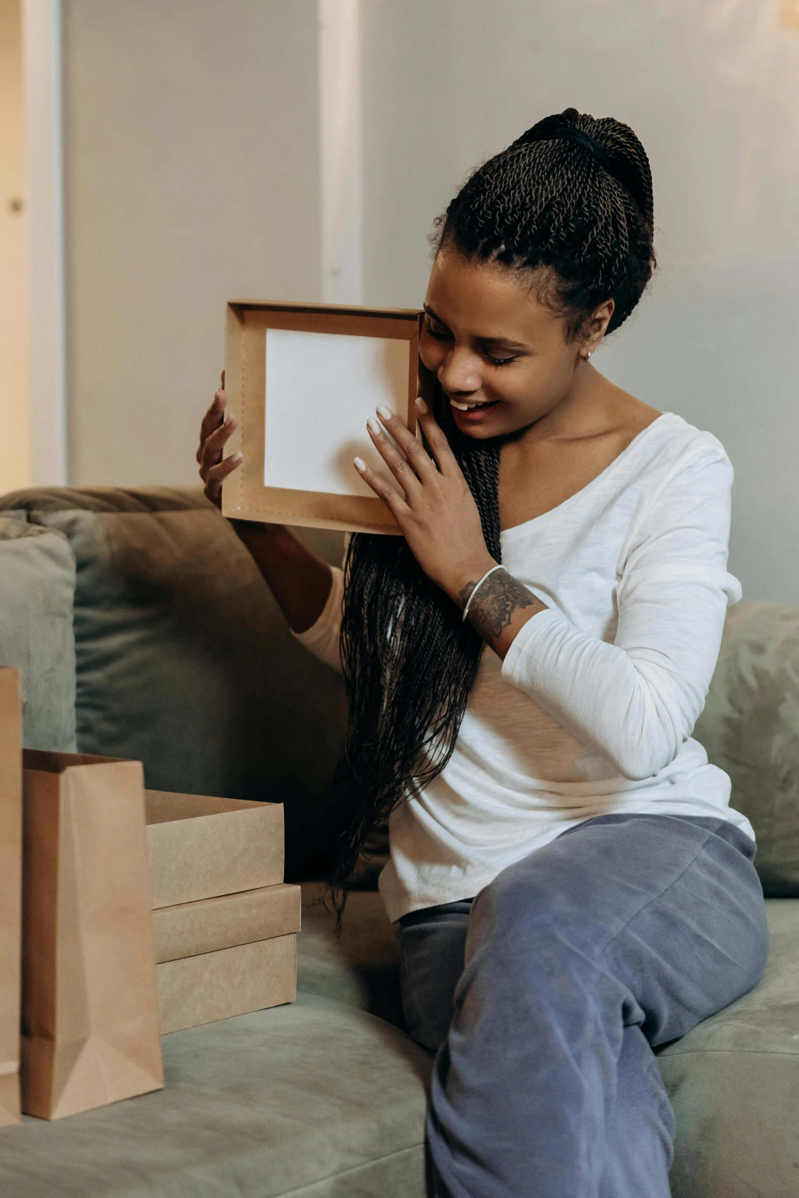 a woman sitting on a couch holding a box, a picture, hugs, photo of a black woman, ecommerce photograph, square pictureframes