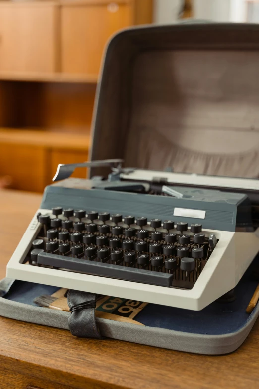 an old typewriter sitting on top of a wooden table, by Carey Morris, private press, circa 1970, in the original box, grey, briefcase