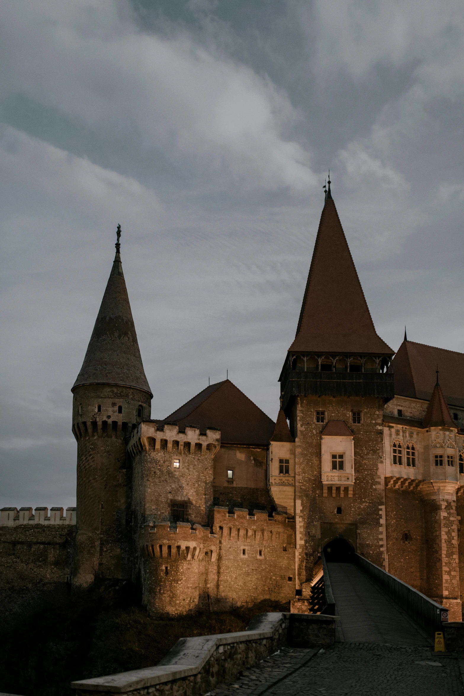 a castle sitting on top of a hill under a cloudy sky, a photo, by Adam Szentpétery, renaissance, gothic lighting, two giant towers, brown, to