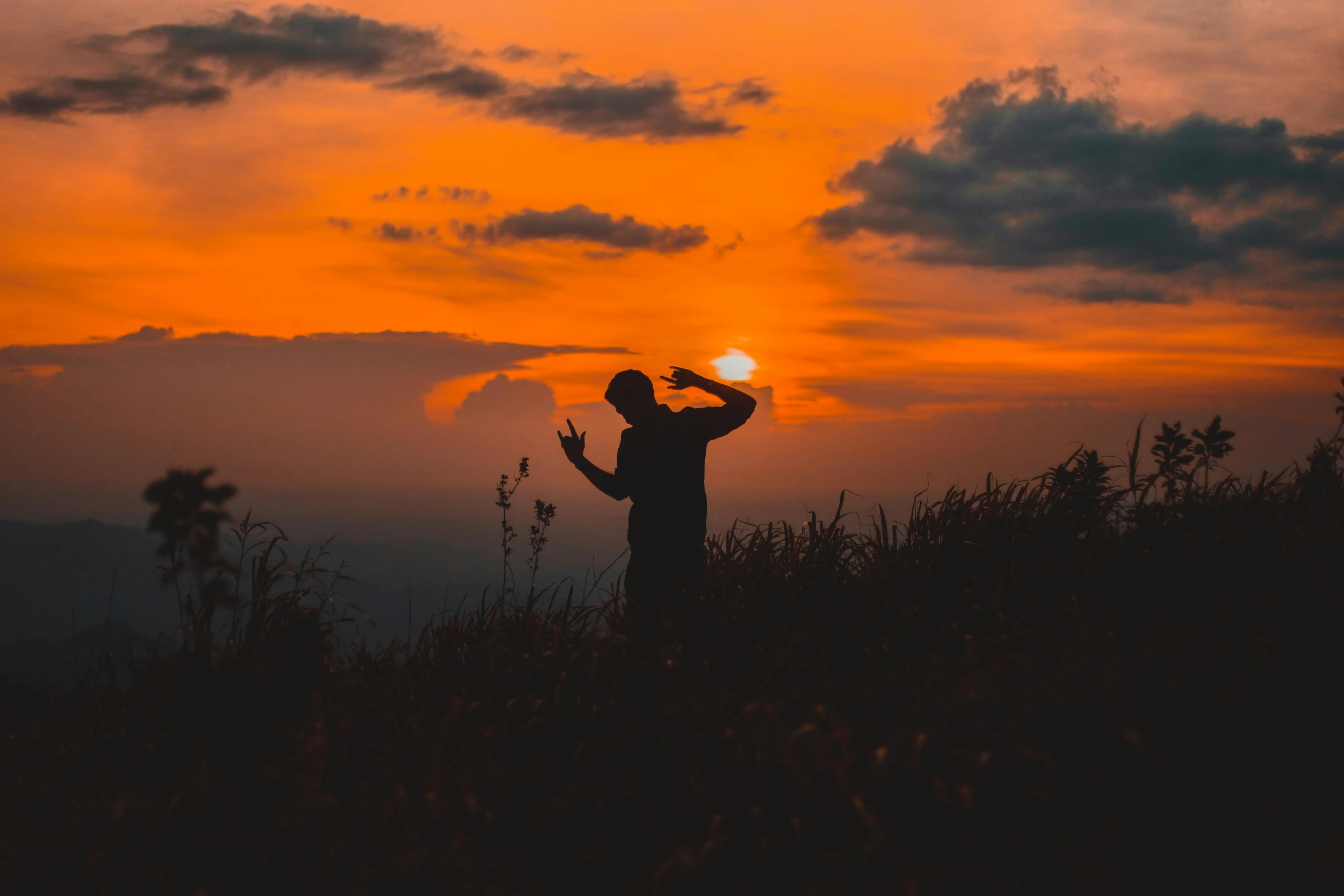 a man standing on top of a grass covered hillside, pexels contest winner, romanticism, orange sun set, dabbing, during an eclipse, profile pic