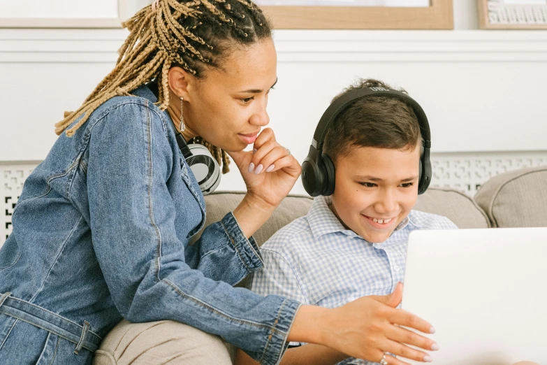 a woman and a child sitting on a couch with a laptop, pexels, wearing black headphones, avatar image, teen boy, teaching