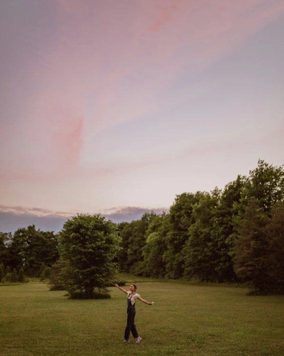 a person in a field throwing a frisbee, by Emma Andijewska, pink skies, low quality photo, on trees, multiple stories