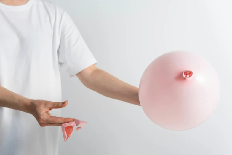 a man in a white shirt holding a pink balloon, by Anna Füssli, trending on unsplash, hyperrealism, porcelain forcefield, surgical impliments, body swelling about to explode, long trunk holding a wand