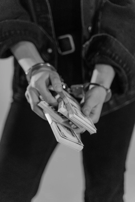 a woman holding a bunch of money in her hands, a black and white photo, unsplash, conceptual art, handcuffed, [ metal ], yung lean, instrument