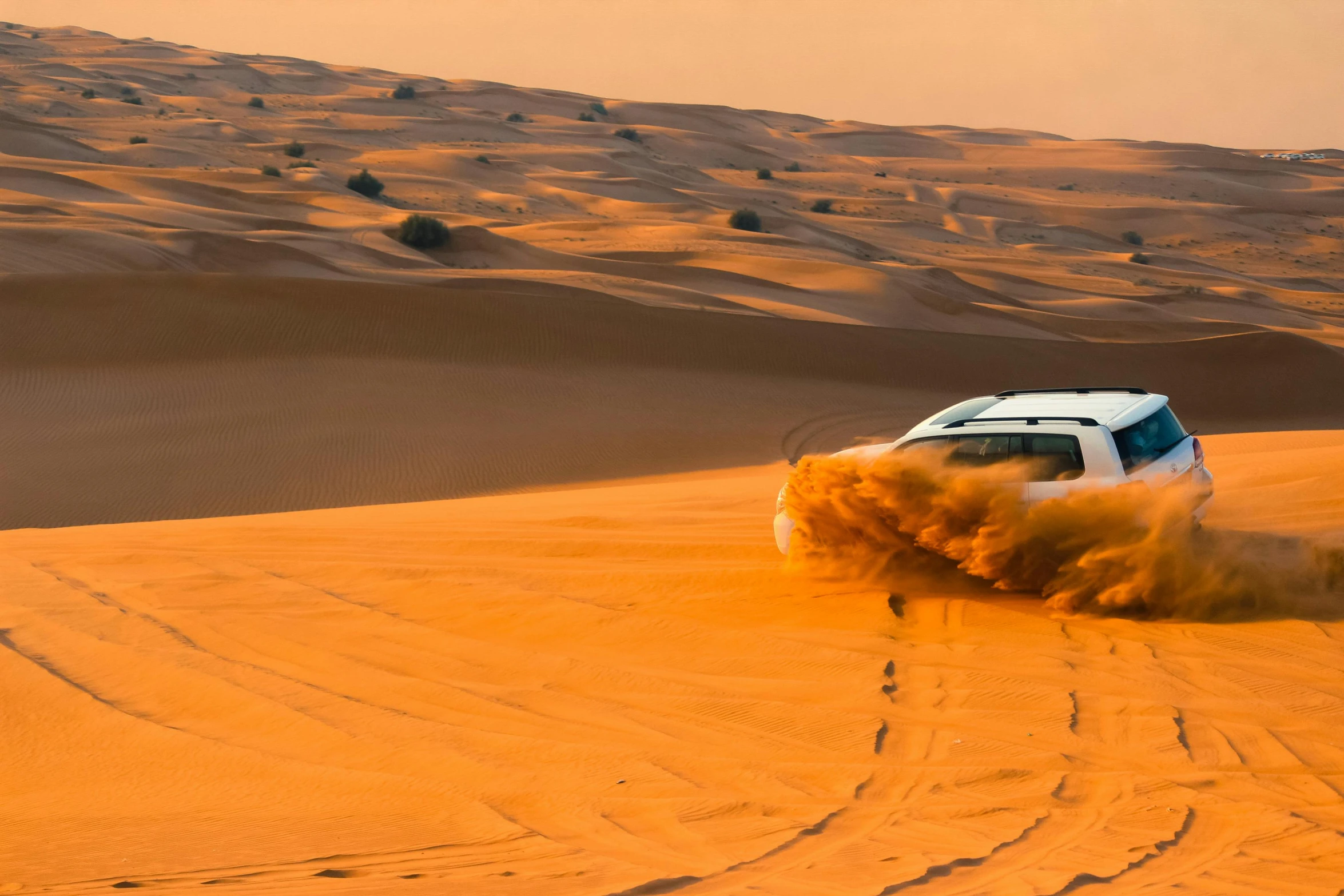 a car that is driving in the sand, in the middle of the desert