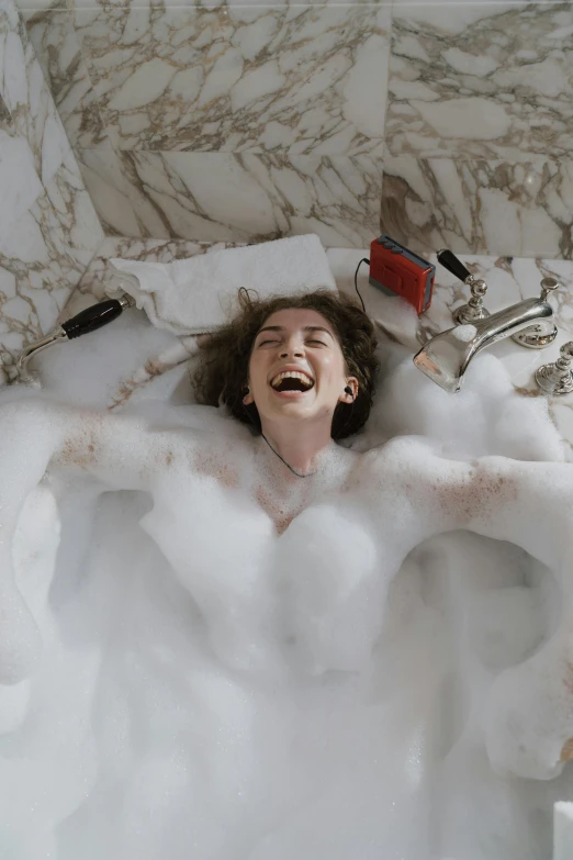 a woman laying in a bath filled with foam, inspired by Nan Goldin, trending on pexels, happening, laughing, timothee chalamet, curls, bells