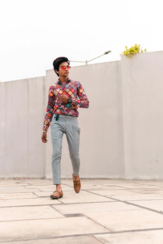 a man walking across a tiled floor next to a wall, by Basuki Abdullah, featured on instagram, colorful outfit, androgynous, full body with dynamic pose, trending on artstion