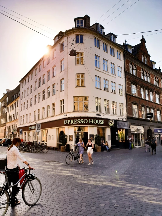 a person riding a bike on a city street, by Jesper Knudsen, happening, house's and shops and buildings, starbucks, profile image