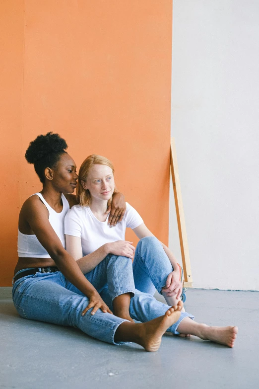 a couple of women sitting next to each other, by Carey Morris, trending on unsplash, renaissance, white and orange, lesbian embrace, mixed race, two buddies sitting in a room