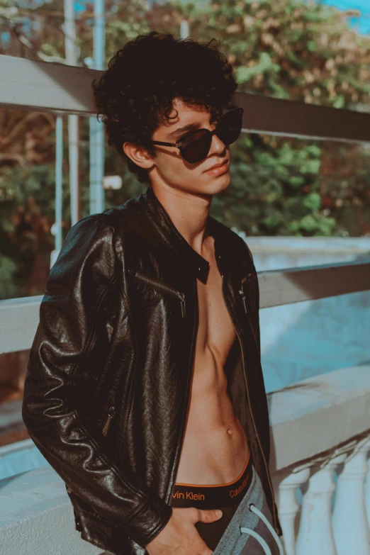 a shirtless young man wearing a black leather jacket, an album cover, by Cosmo Alexander, trending on pexels, sholim, cynthwave, lean man with light tan skin, sun glasses