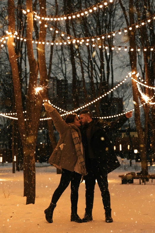 two people standing next to each other in the snow, pexels contest winner, romanticism, string lights, park in background, quebec, celebrating