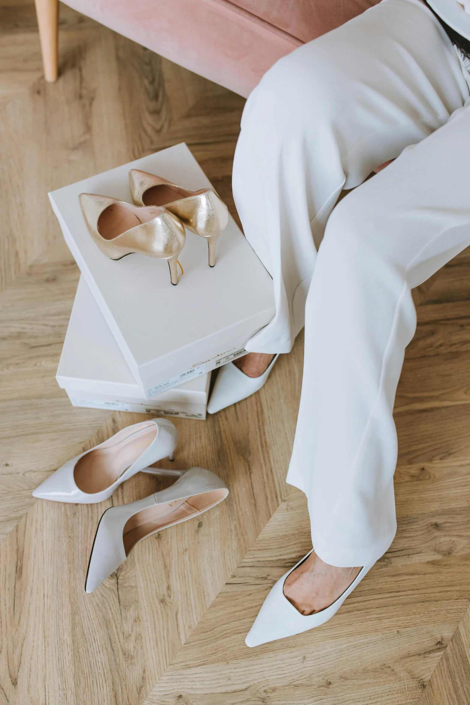 a woman sitting on top of a wooden floor next to a pink couch, inspired by Karl Buesgen, trending on pexels, renaissance, wearing a white tuxedo, silk shoes, silver，ivory, white box