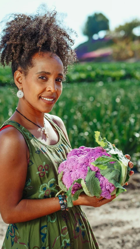 a woman holding a bunch of purple flowers, east african man with curly hair, confident holding vegetables, promo photo, portrait image