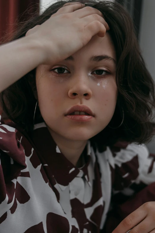 a young girl sitting at a table with her hand on her head, an album cover, trending on pexels, hyperrealism, jimin\'s right eyelid swollen, beautiful crying! android woman, teenage boy, portrait soft low light