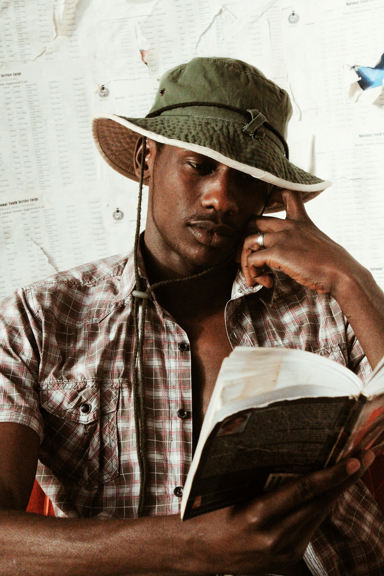 a man reading a book while wearing a hat, adut akech, '0 0 s nostalgia, rugged, trending photo