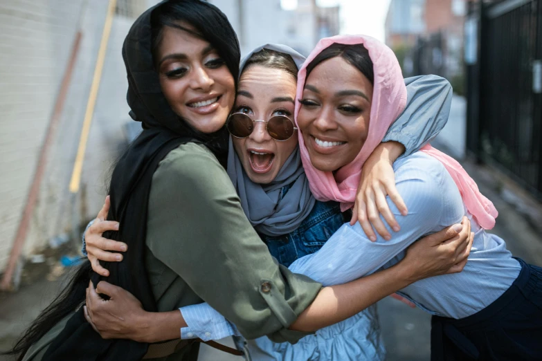 a group of women standing next to each other on a street, pexels contest winner, hurufiyya, loving embrace, diverse costumes, three women, wearing a head scarf