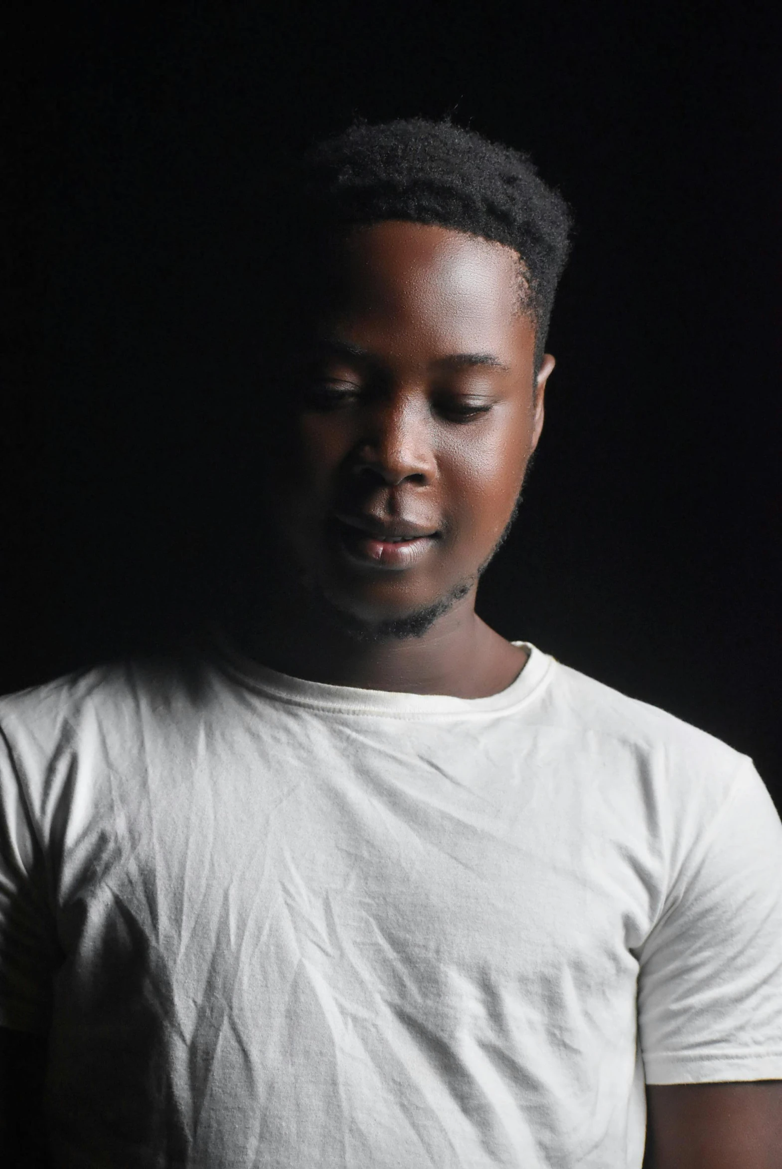 a man in a white shirt holding a cell phone, an album cover, inspired by David Bailly, pexels contest winner, grey skin, frontal pose, ( ( dark skin ) ), portrait soft low light