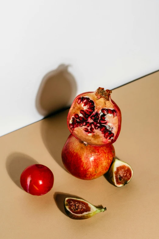 a pomegranate and two figurines on a table, a still life, trending on pexels, glossy surface, golden apple, crisp image, seeds