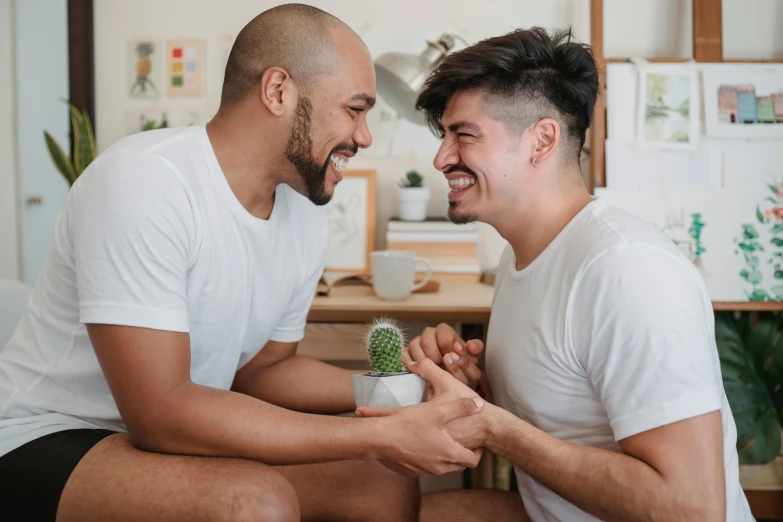 a couple of men sitting on top of a bed next to each other, pexels contest winner, earing a shirt laughing, aussie baristas, holding each other hands, hispanic