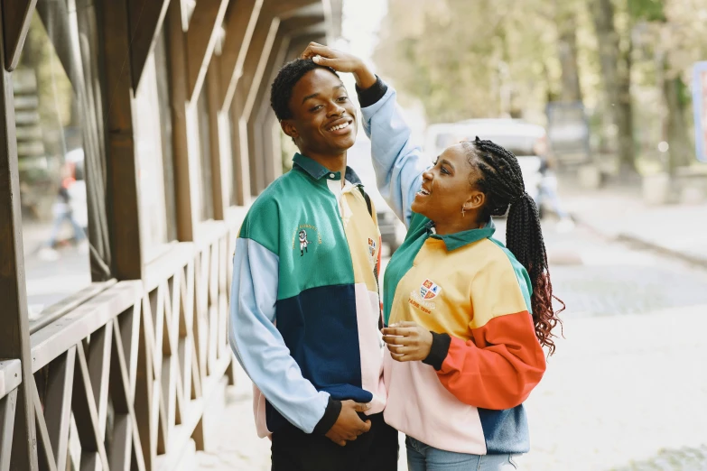 a man and a woman standing next to each other, trending on pexels, colorful uniforms, black teenage boy, happy couple, vintage aesthetic