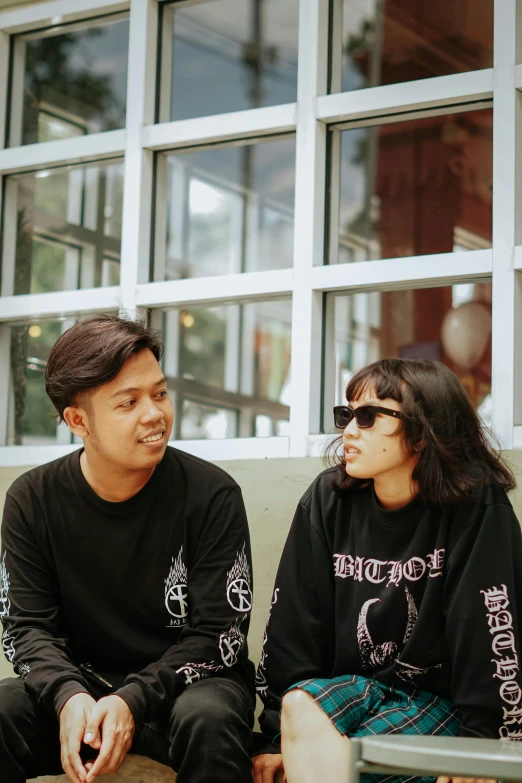 a man and a woman sitting on a bench, pexels contest winner, wearing a black sweater, band merchandise, batik, cynthwave