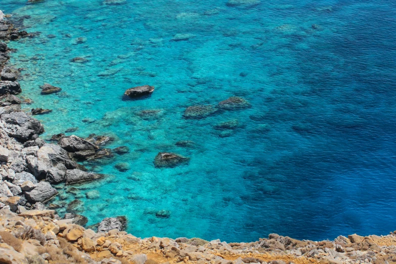 a large body of water next to a rocky shore, pexels contest winner, hurufiyya, warm shades of blue, glass antikythera, thumbnail, coral sea bottom