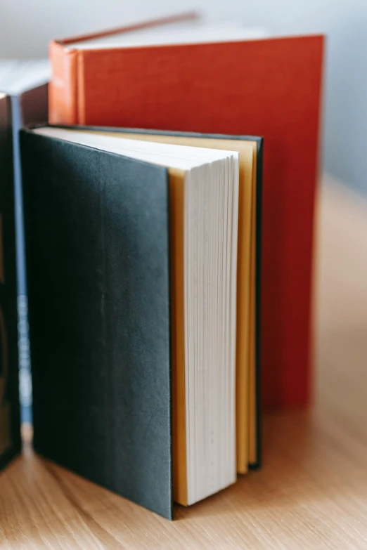 a stack of books sitting on top of a wooden table, zoomed in, upclose, colour photo, no - text no - logo