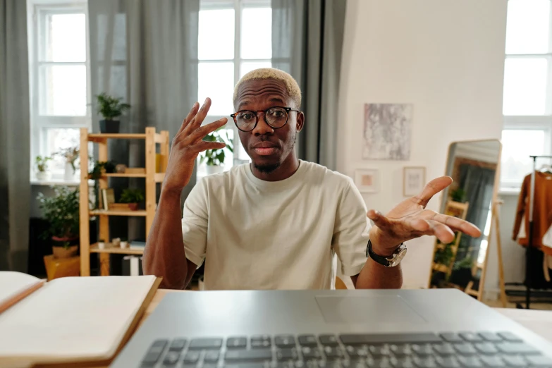 a man sitting in front of a laptop computer, trending on pexels, happening, shrugging arms, black people, nerdy music teacher with phd, low quality photo