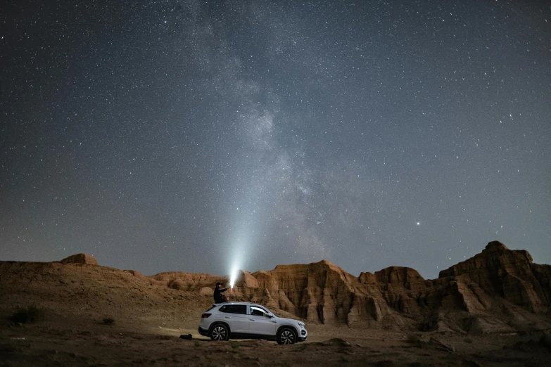 a person standing on top of a car in the desert, unsplash contest winner, light and space, set in observatory at night, subaru, very bright white light, over a cliff