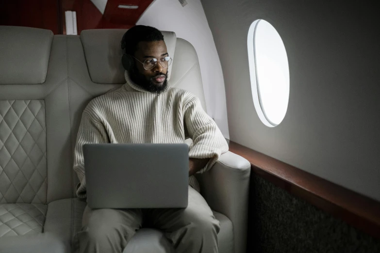 a man sitting in an airplane with a laptop, pexels contest winner, afrofuturism, sitting on a red button, home office, jeffrey wright, airing in 2 0 2 3