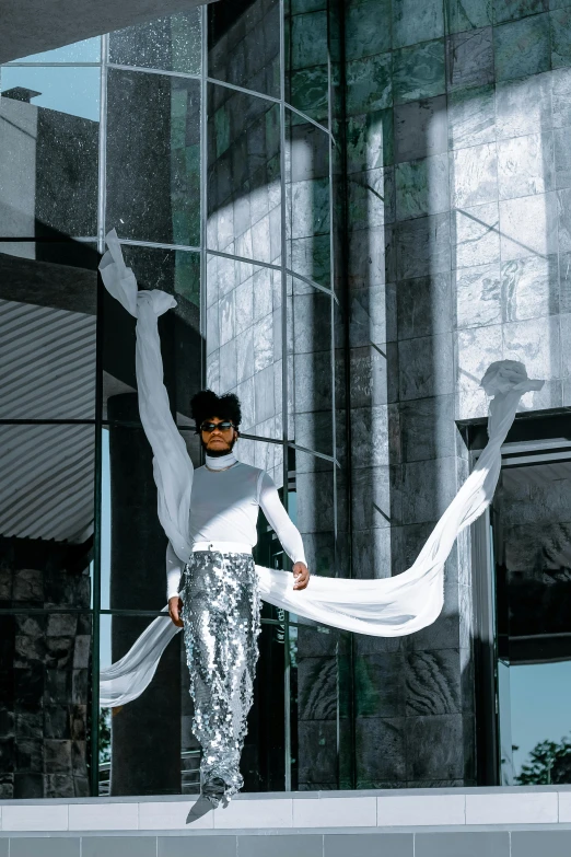 a man in a white shirt and silver pants, inspired by hajime sorayama, pexels contest winner, twirling, silks, exterior shot, afro - futurist style