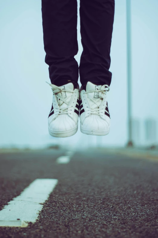 a person standing on a street with their feet in the air, an album cover, pexels contest winner, running shoes, jetpack, grainy, teenage