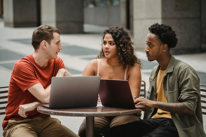 three people sitting at a table with laptops, pexels contest winner, college students, diverse, in a city square, avatar image