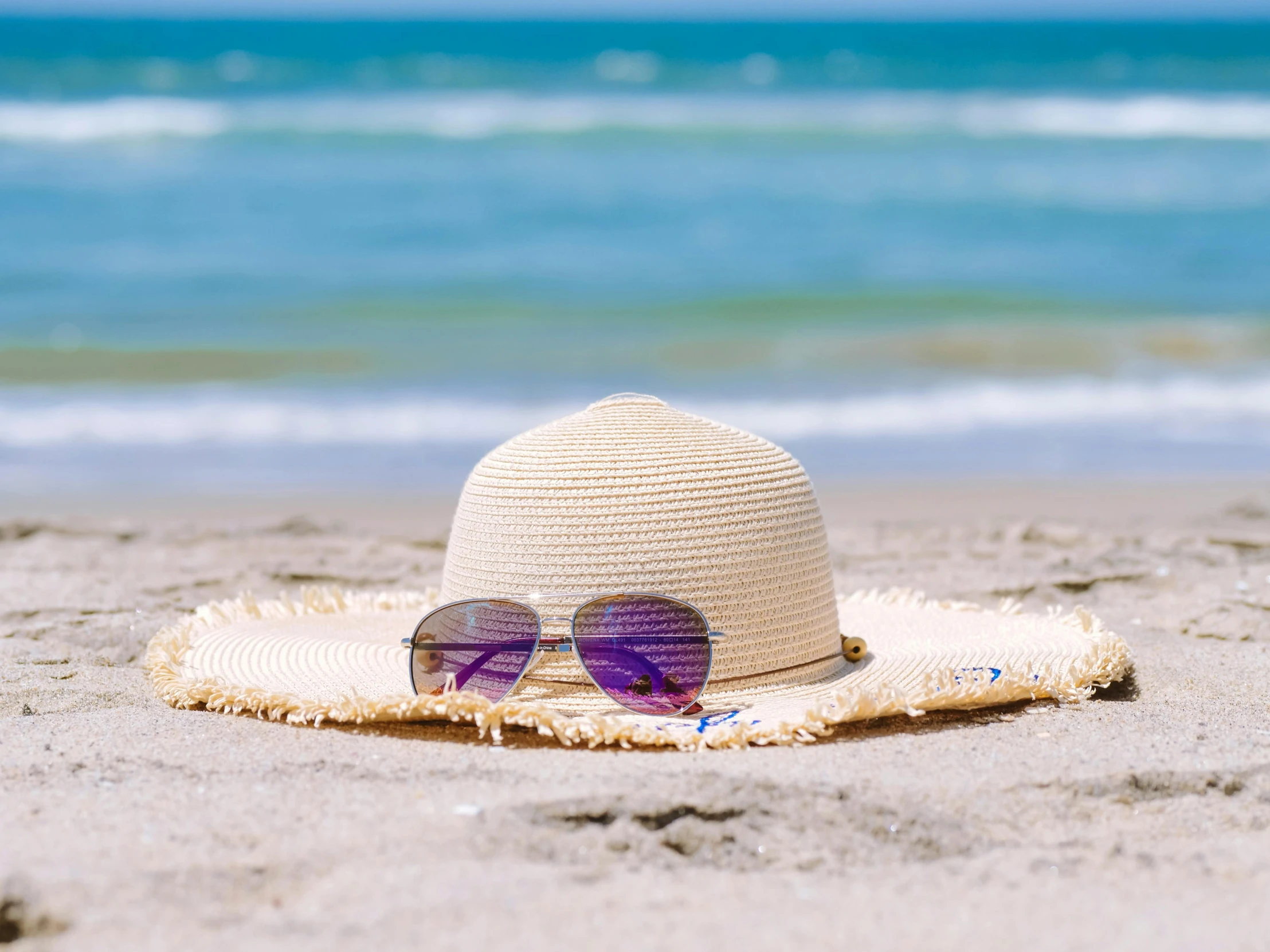 a hat and sunglasses on a beach near the ocean, by Carey Morris, pexels contest winner, purple sand, hot summer sun, hot and humid, white sand