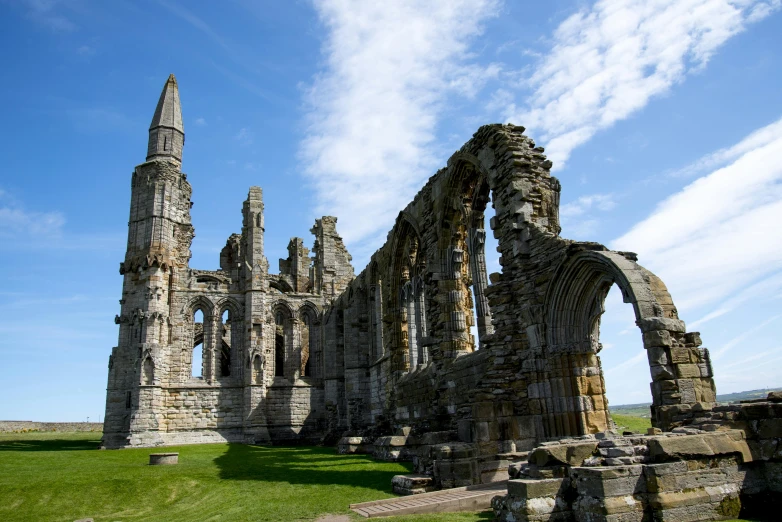 a large stone building sitting on top of a lush green field, by Thomas Barker, pexels contest winner, romanesque, huge support buttresses, yorkshire, shoreline, square