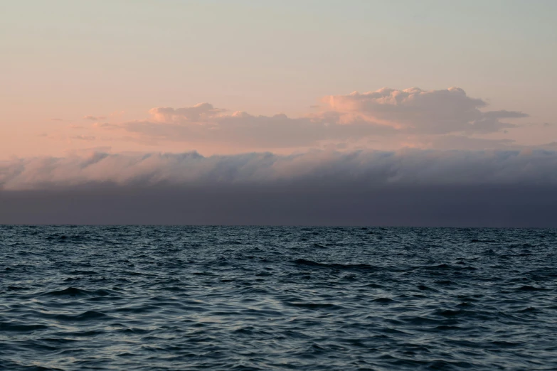 a large body of water under a cloudy sky, a picture, unsplash, romanticism, light pink mist, viewed from the ocean, ignant, joel meyerowitz