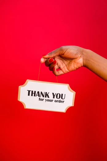 a person holding a sign that says thank you for your order, an album cover, by Julia Pishtar, pexels, essence, red and gold, product label, thin