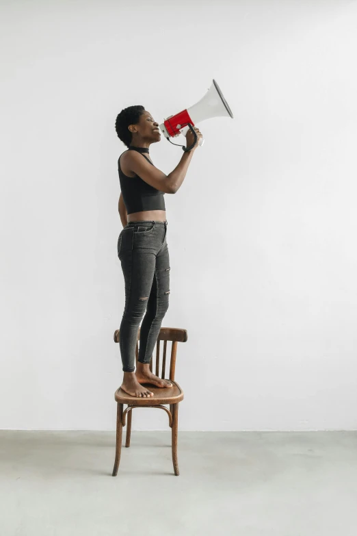 a woman standing on a chair holding a megaphone, trending on unsplash, black arts movement, fullbody photo, profile image, color photo, small