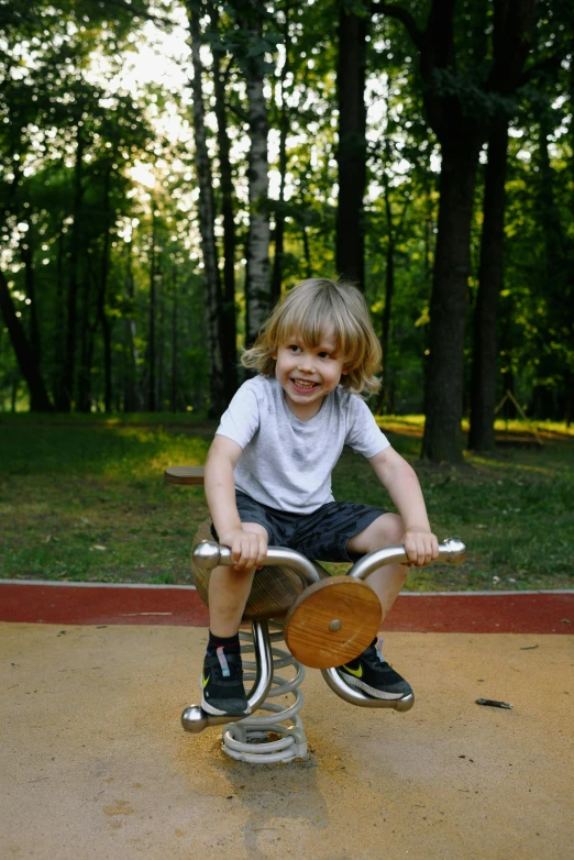 a little boy riding a bike in a park, a picture, by Attila Meszlenyi, pexels contest winner, playful smirk, 15081959 21121991 01012000 4k, carousel, blond