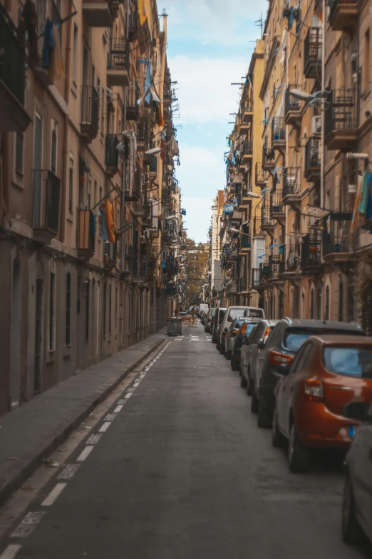 a narrow street lined with parked cars next to tall buildings, by Modest Urgell, spain, gen z, square, low quality photo