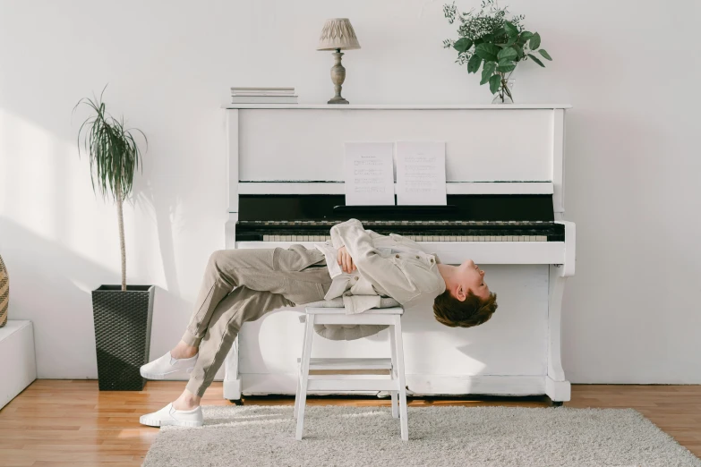 a man laying on a chair in front of a piano, pexels contest winner, aestheticism, white finish, standing upright, stressing out, easy to use