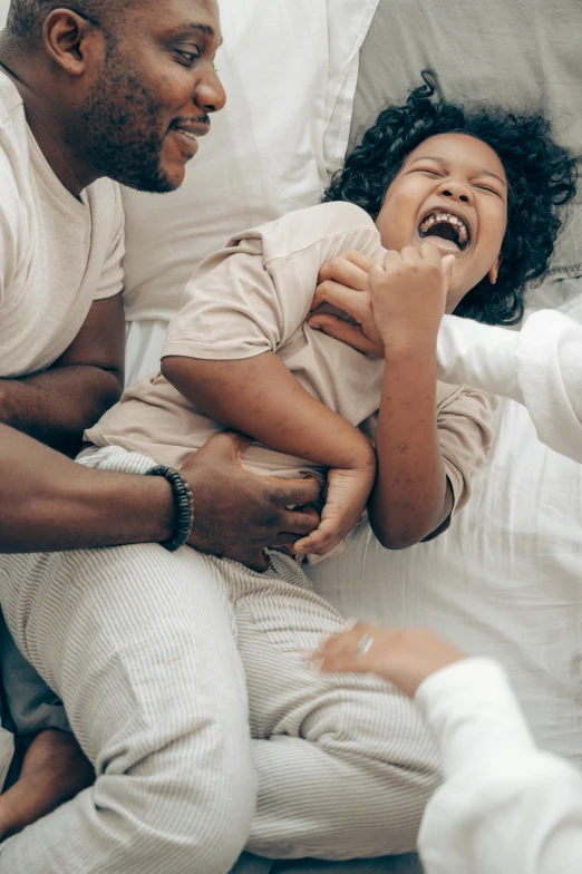 a man and woman laying in bed with a baby, pexels contest winner, incoherents, head bent back in laughter, with a kid, hugging her knees, heavy gesture style closeup