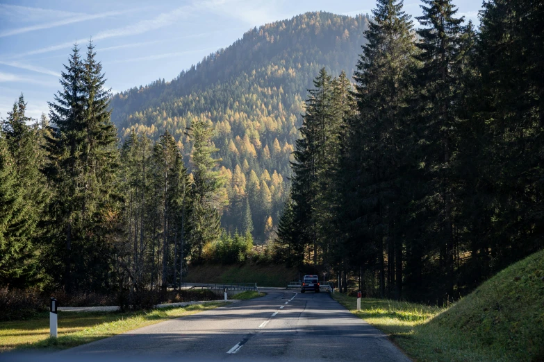 a car that is sitting on the side of a road, by Werner Gutzeit, pexels contest winner, spruce trees on the sides, mid fall, slovakia, sunny day time